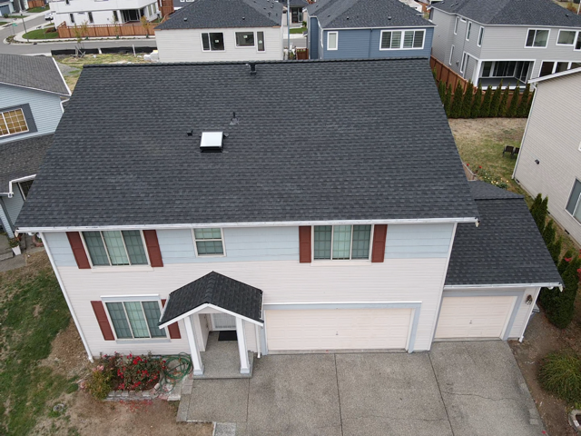 Two-story house with dark gray roof and light blue siding, red shutters, and two-car garage.