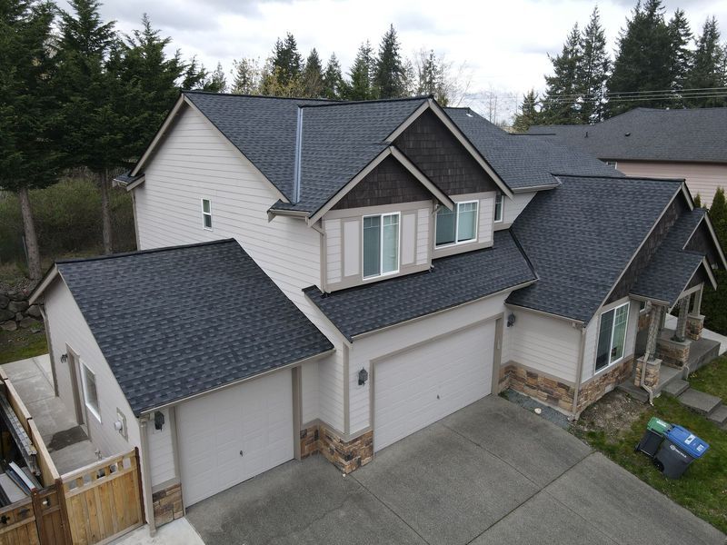 Beige two-story house with a dark gray shingle roof and a two-car garage.