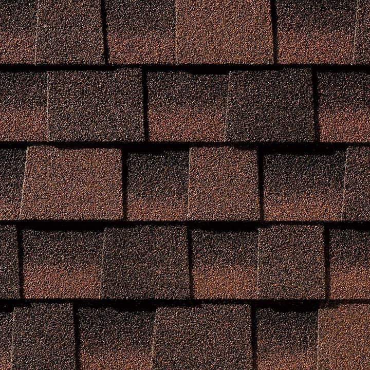 Close-up of asphalt roof shingles in shades of brown and dark red.