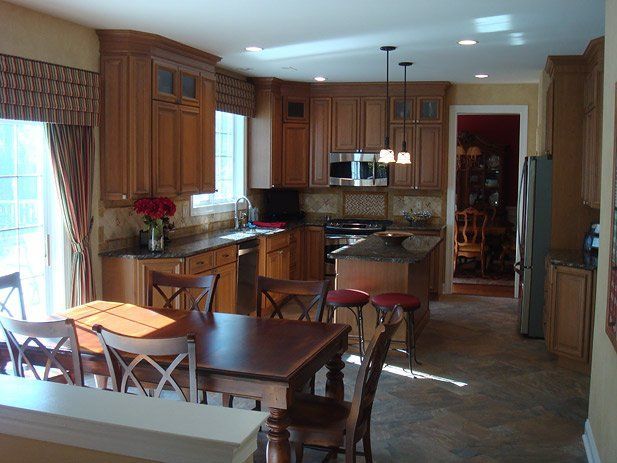 Kitchen with wood cabinets, island, and dining table; natural light through a sliding door.