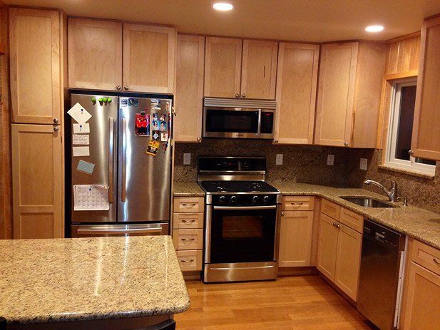 Kitchen with light wood cabinets, stainless steel appliances, granite countertops, and hardwood floors.