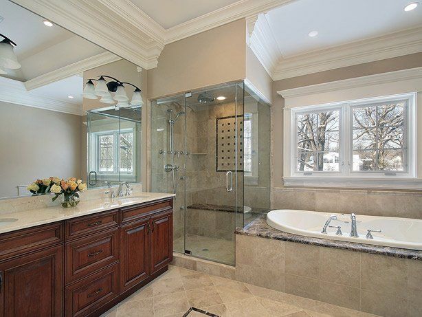Luxurious bathroom with dark wood vanity, glass shower, and white bathtub near a window.
