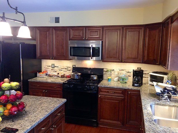 Kitchen with dark brown cabinets, granite countertops, and black appliances.