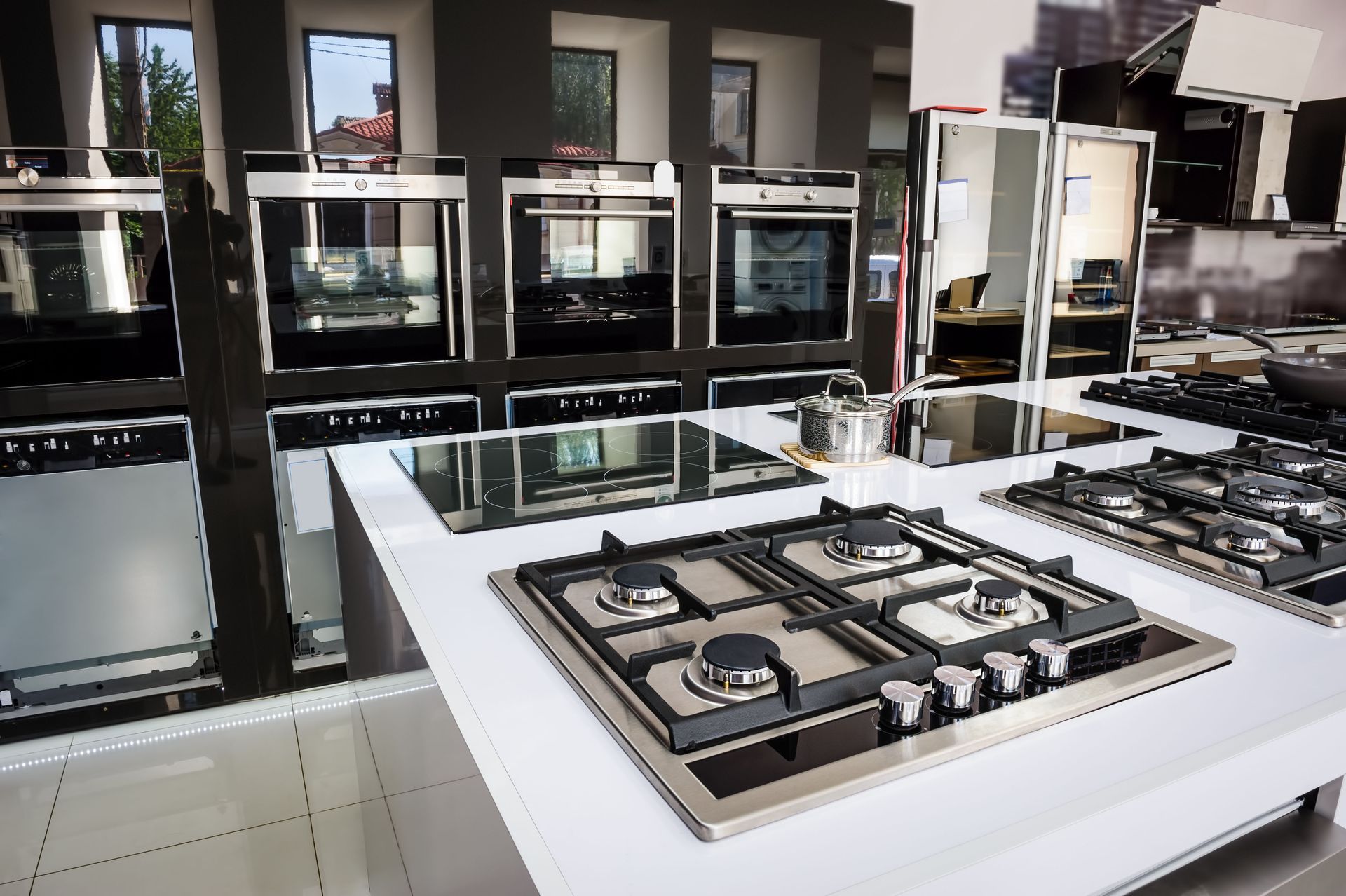 Kitchen appliances showroom: ovens, cooktops, and countertops on display.