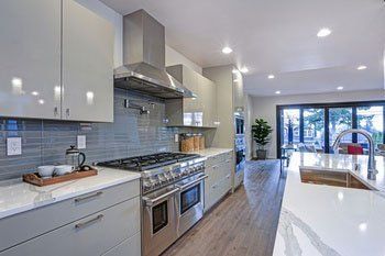 Modern kitchen with stainless steel appliances, gray cabinets, and a view to outside.