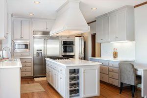 White kitchen with island, stainless steel appliances, and built-in wine rack.