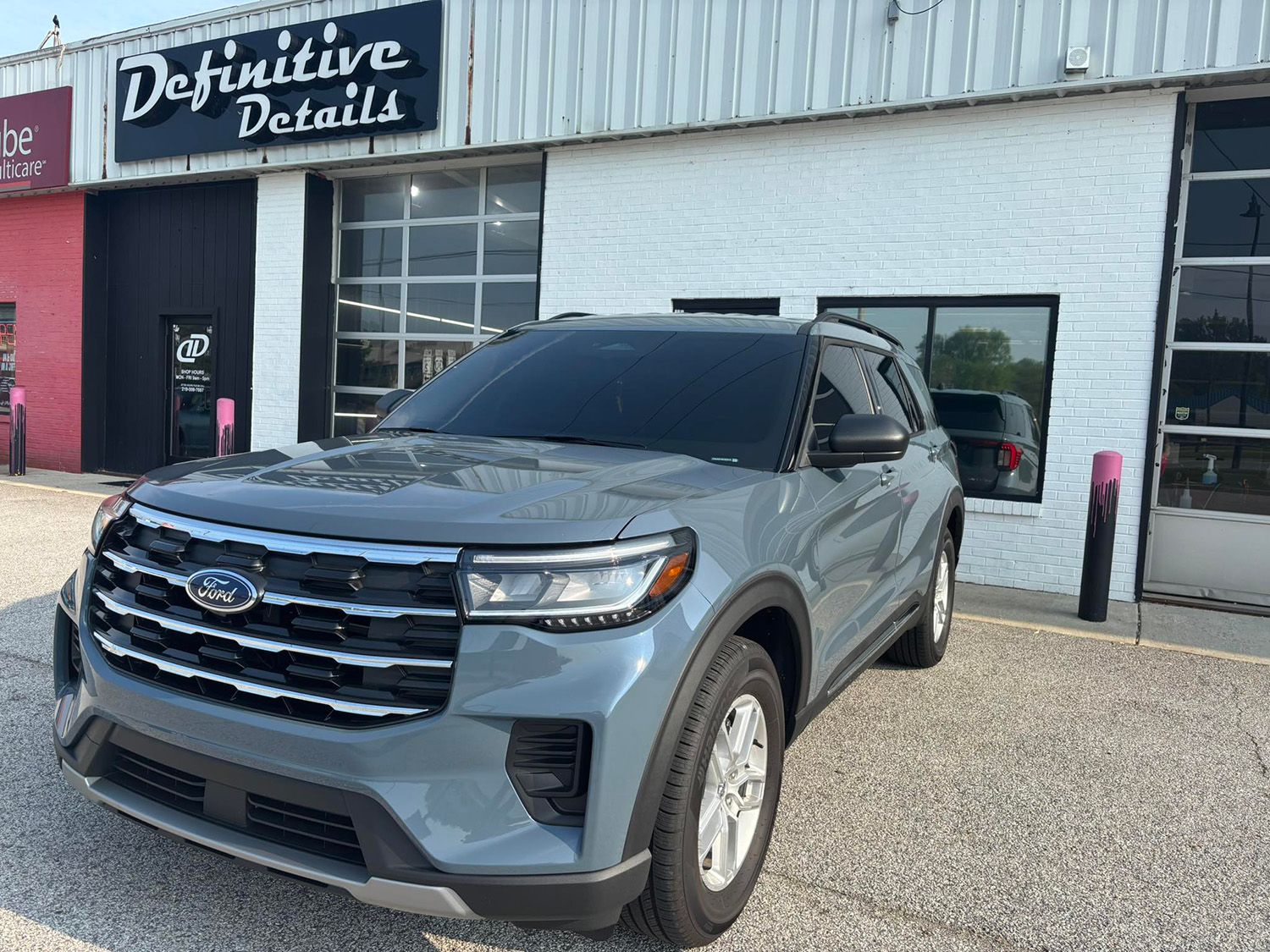 Gray Ford Explorer parked in front of a business with the sign 