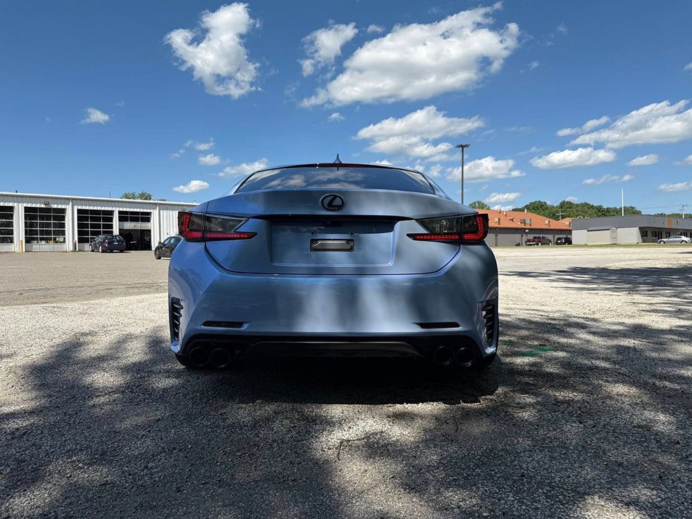 Rear view of a blue Lexus sports coupe parked outdoors on a sunny day.