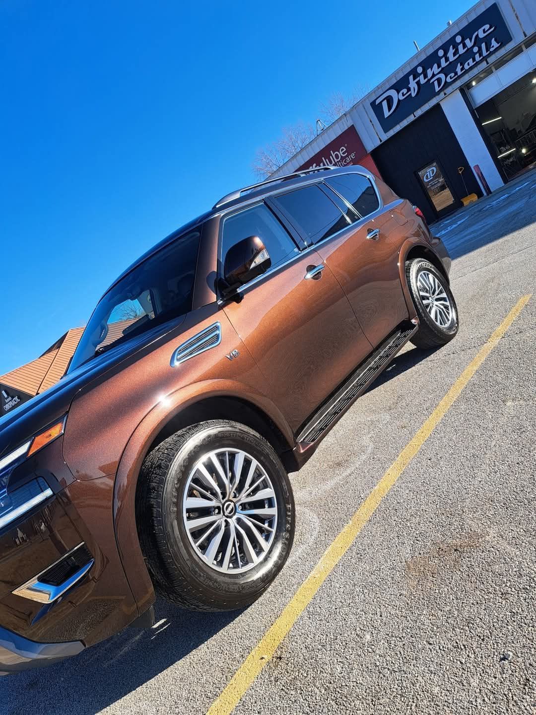 Brown SUV parked outside a car detailing shop under a clear blue sky.