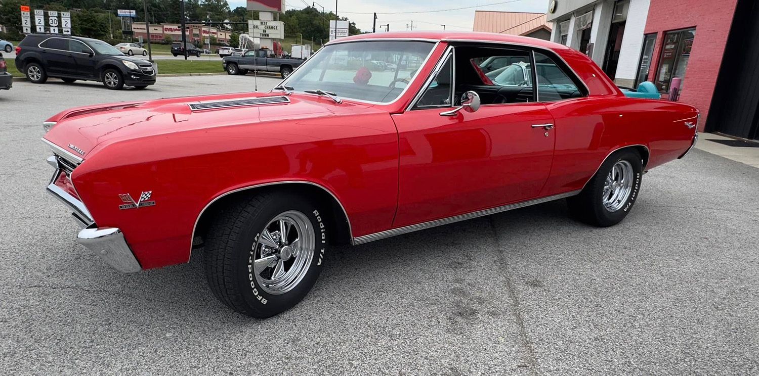 Red 1967 Chevrolet Chevelle SS parked on gray pavement. Chrome wheels, bright red paint.