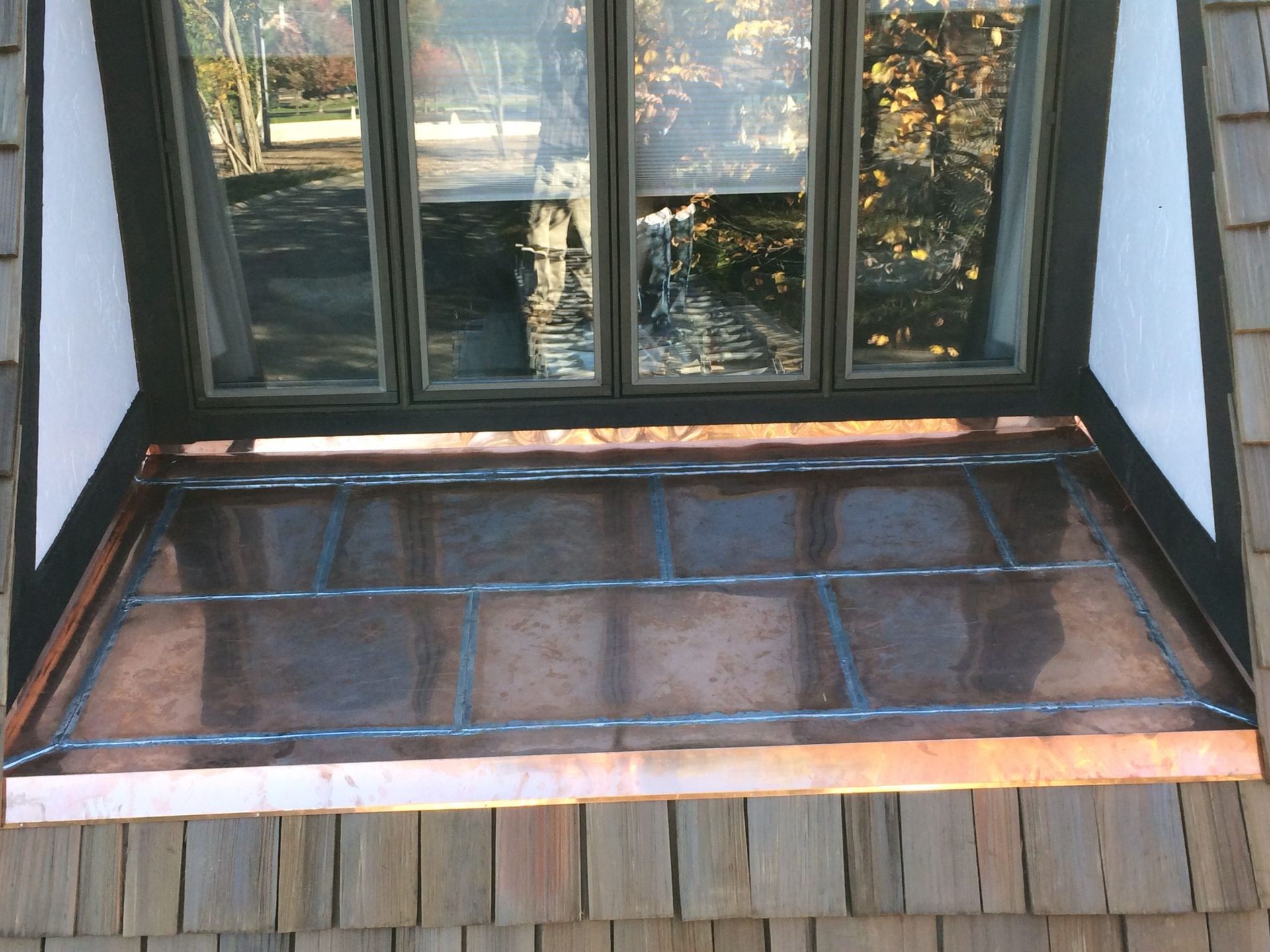 Porch window with dark trim and a copper roof over a brick ledge