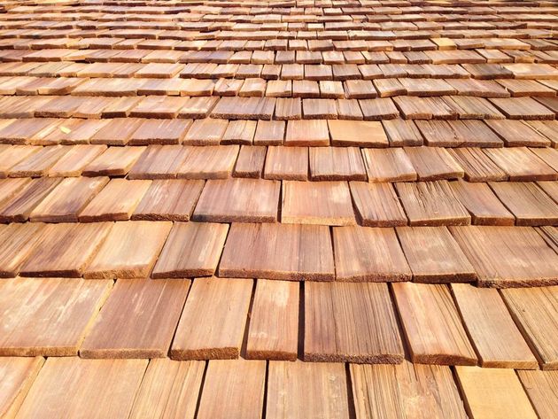 Close-up of overlapping wooden roof shingles in warm brown tones