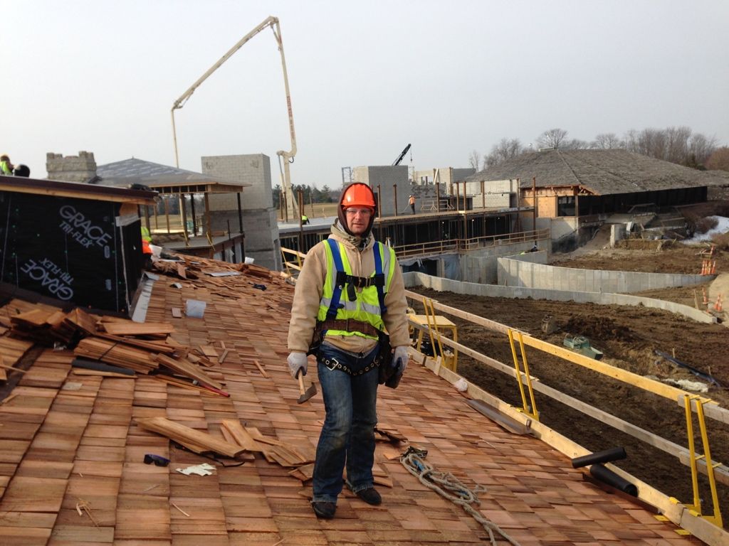 Construction worker in hard hat and vest walking on a rooftop at a building site