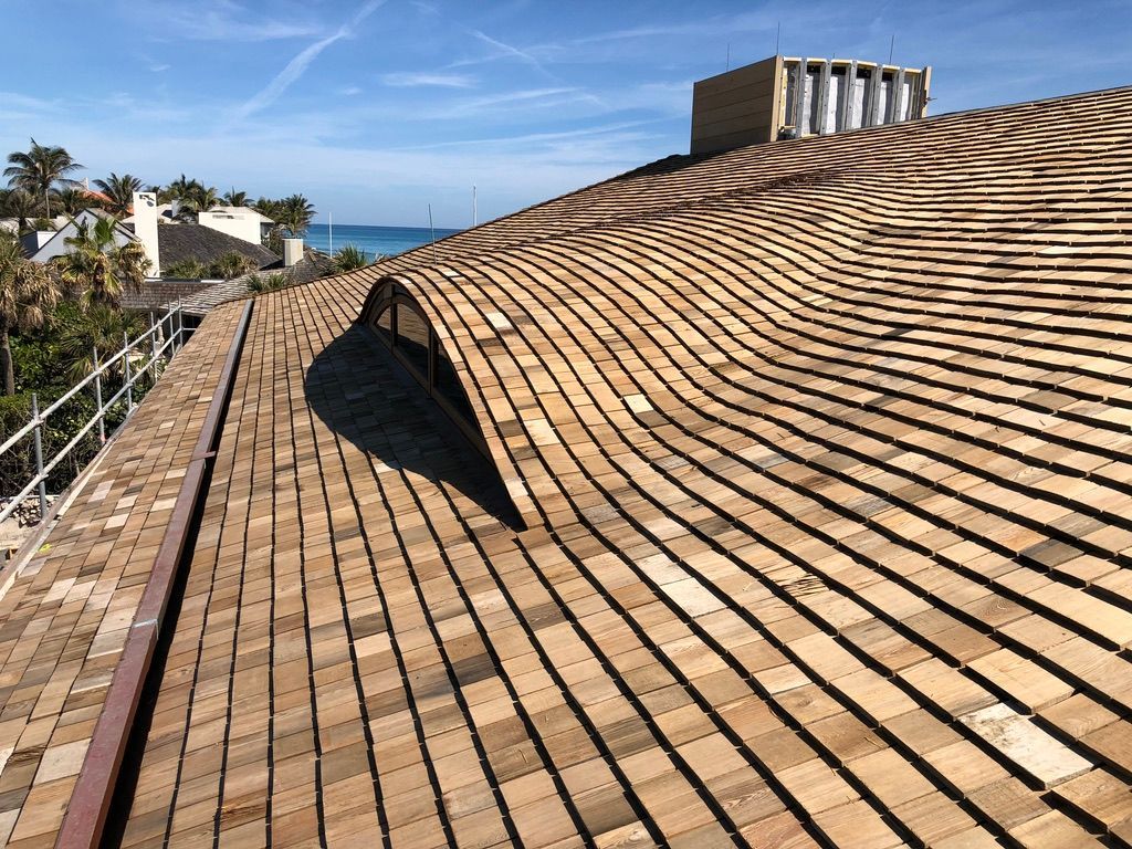 Rooftop with curved brown shingles overlooking the ocean on a sunny day