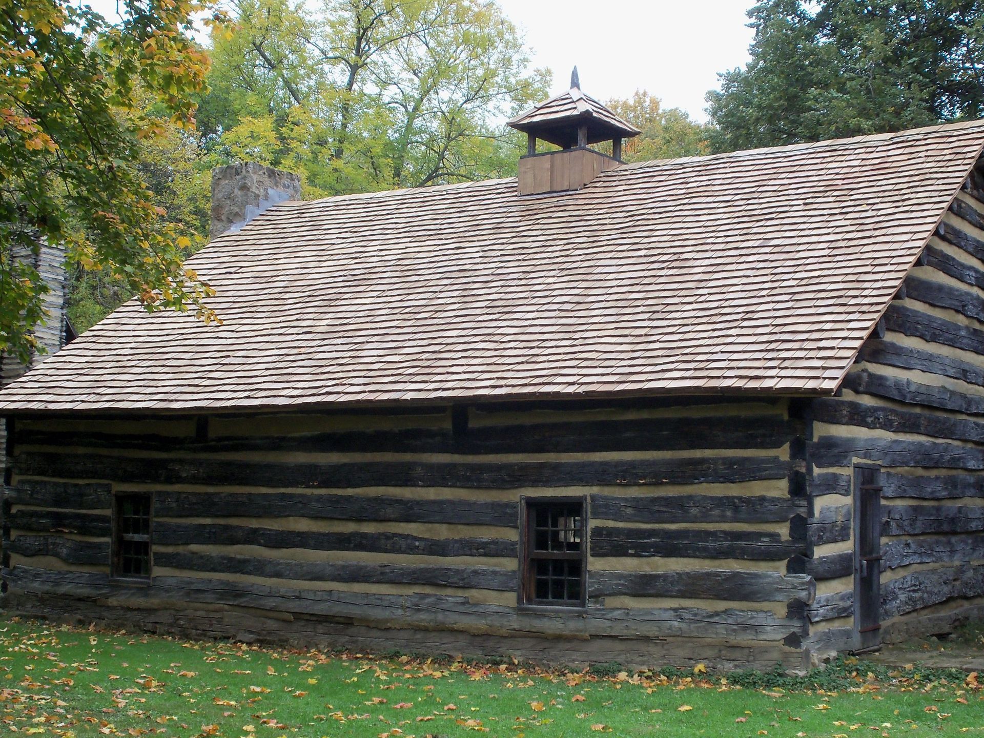 Rustic log cabin with a shingled roof in a wooded setting