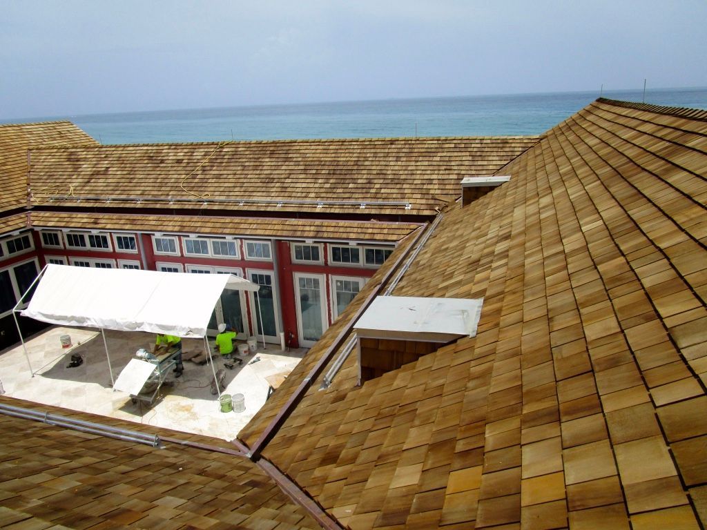 Rooftop terrace with white awnings, tiled roofs, and the sea visible in the background.