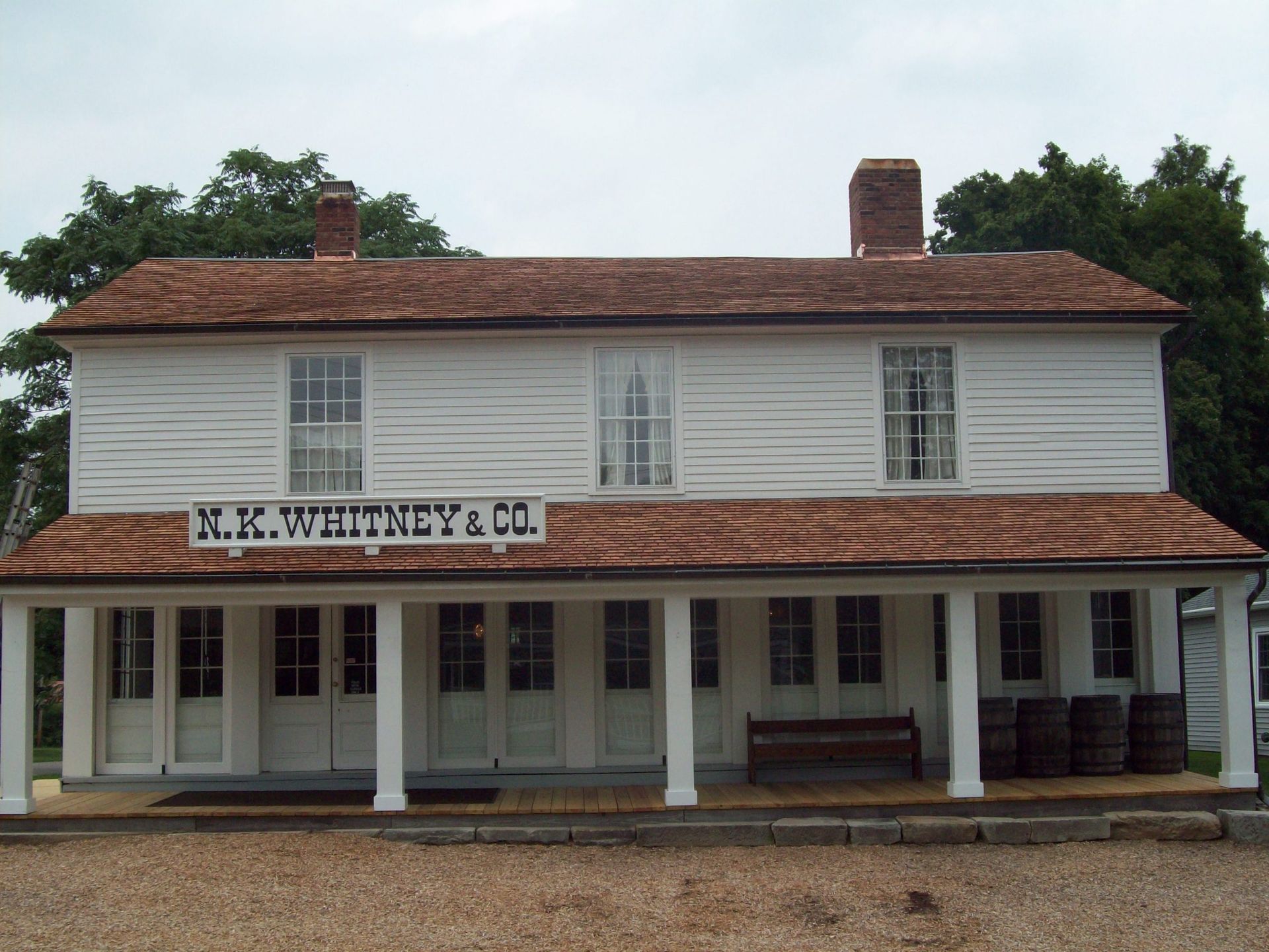 Historic white two-story storefront with a red roof and porch, labeled “H.K. Wrenchy & Co.”