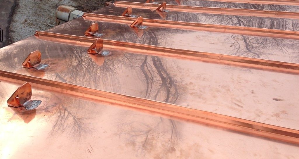Copper pipes laid in rows on a concrete surface, with small fixtures attached near one end.