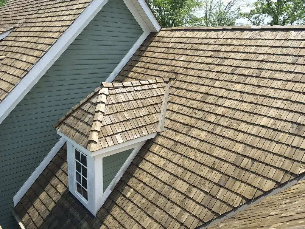 Roof with tan shingles and a small dormer on a house exterior