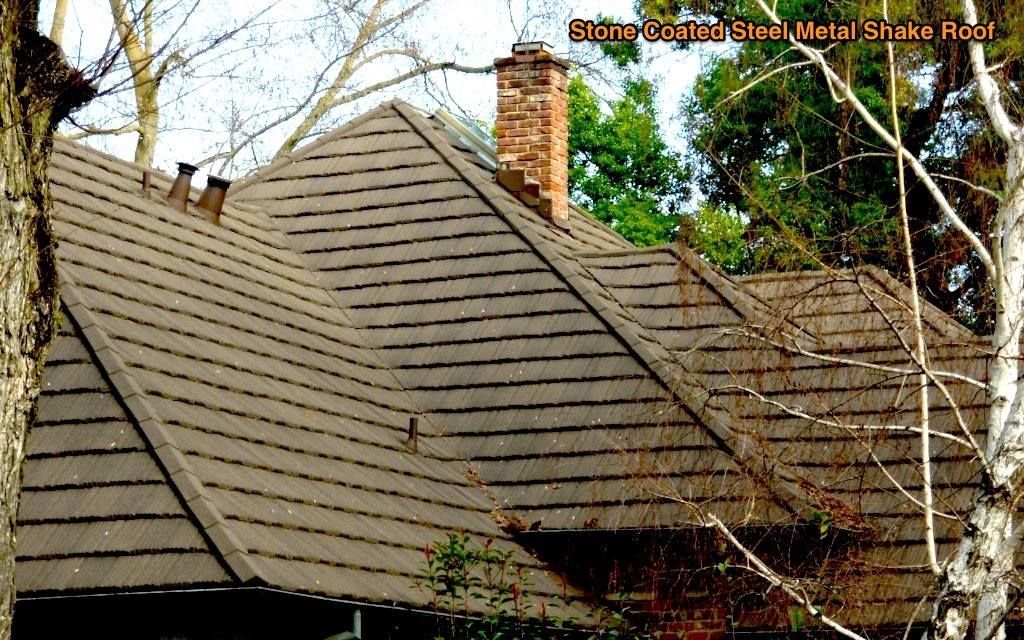 Dark gray shingled roof with a brick chimney and leafless tree branches in the foreground