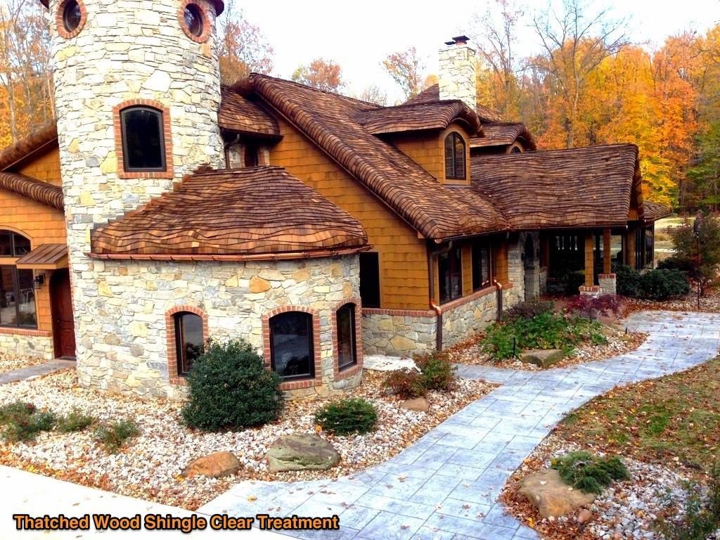 Large rustic stone-and-wood lodge with a tower, autumn trees, and a curved stone path