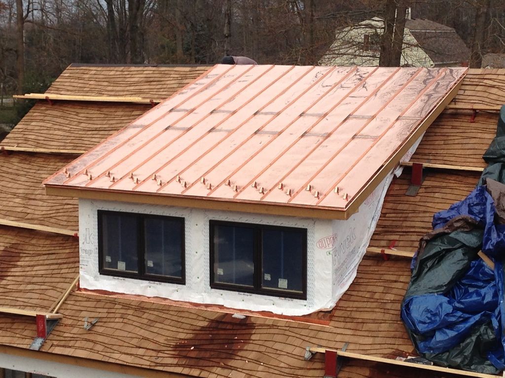 House under construction with copper-colored roof and two front windows