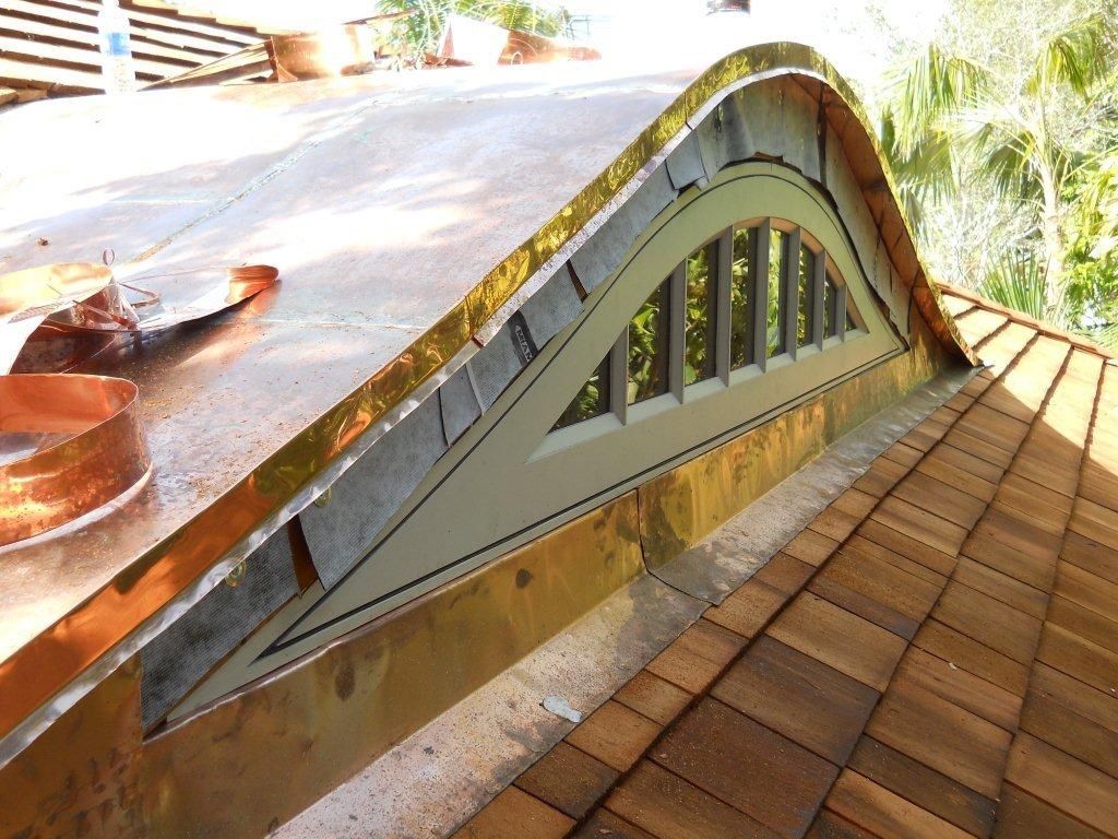 Roof with curved skylight and shingles on a sunlit house exterior