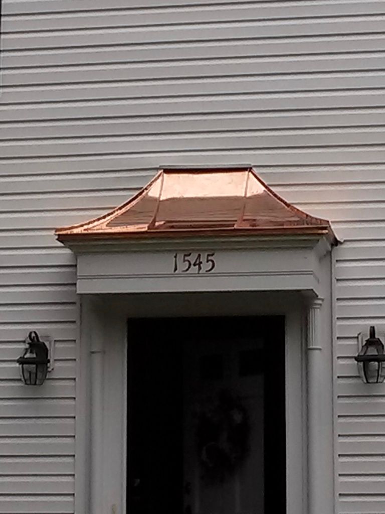 Front entry with copper roof, house number 1545, and wall lanterns on white siding