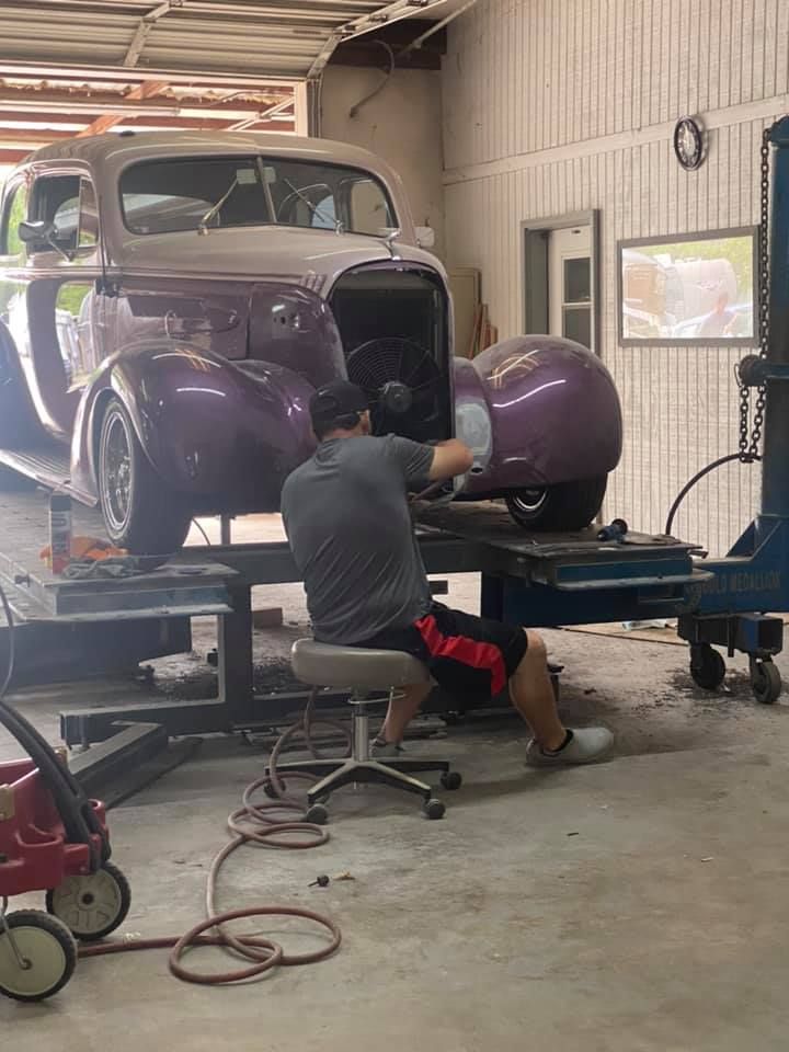 a man is working on a purple car in a garage .