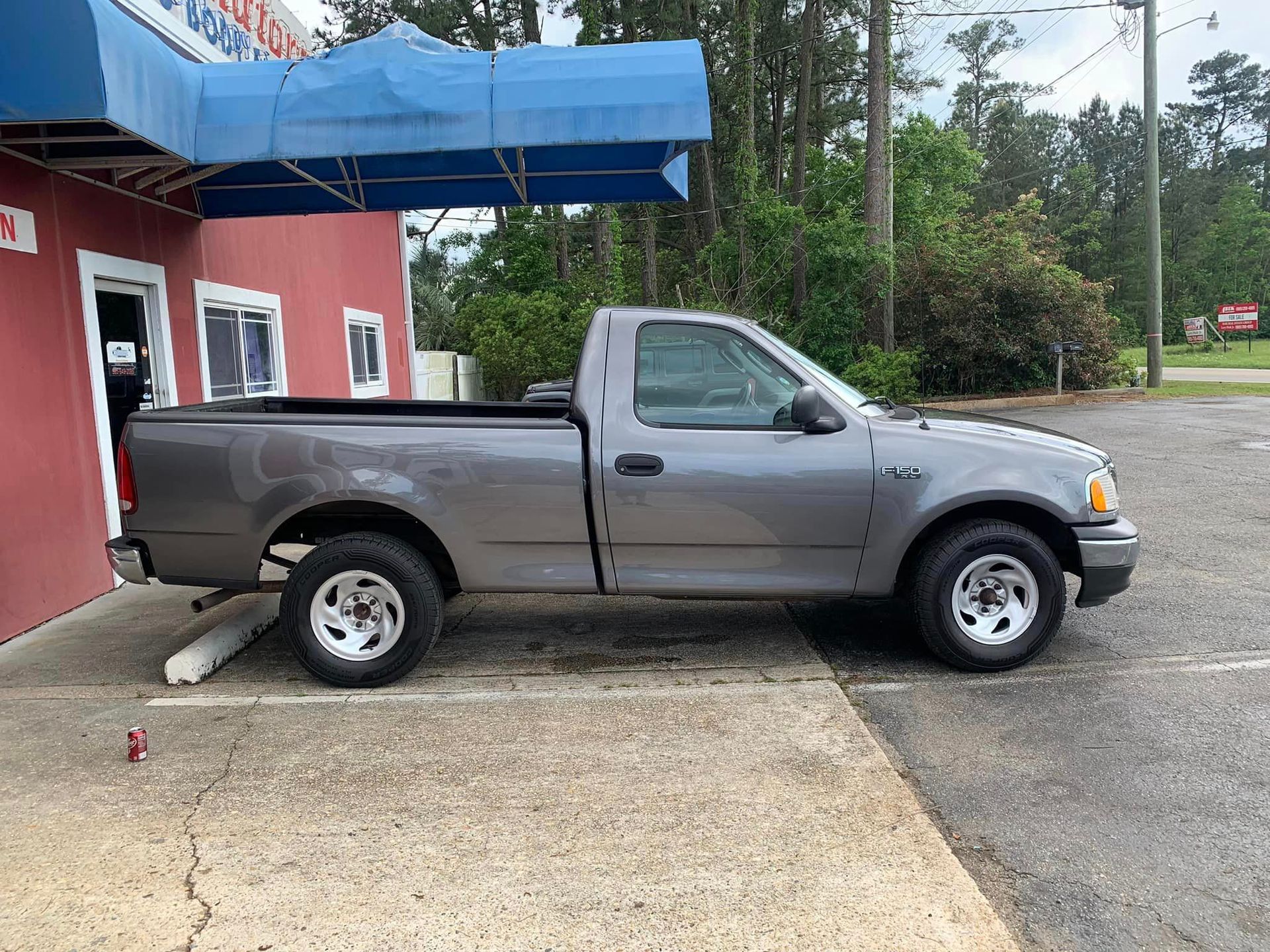 a gray truck is parked in a parking lot in front of a building .