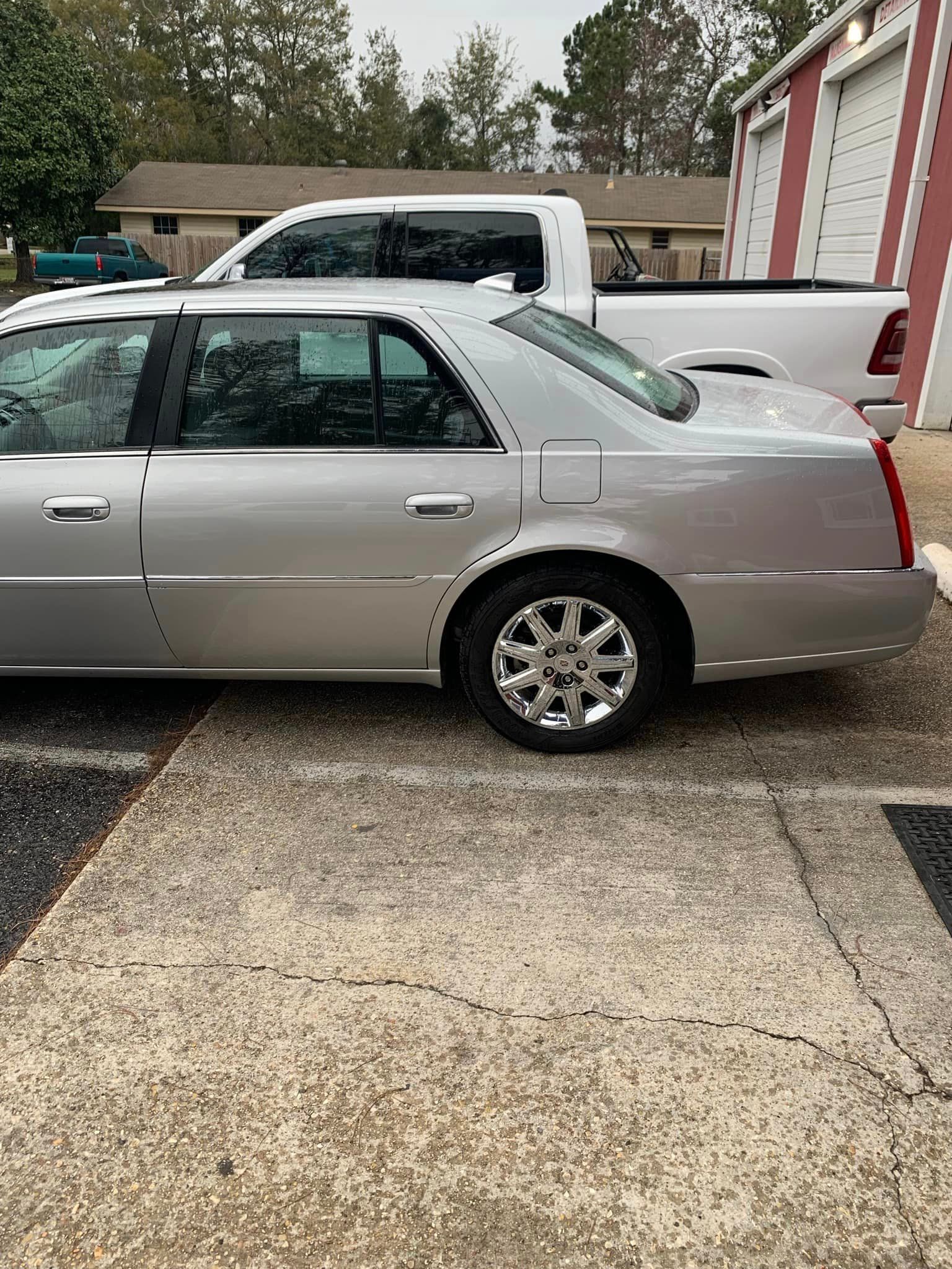 a silver car is parked in a parking lot next to a white truck .