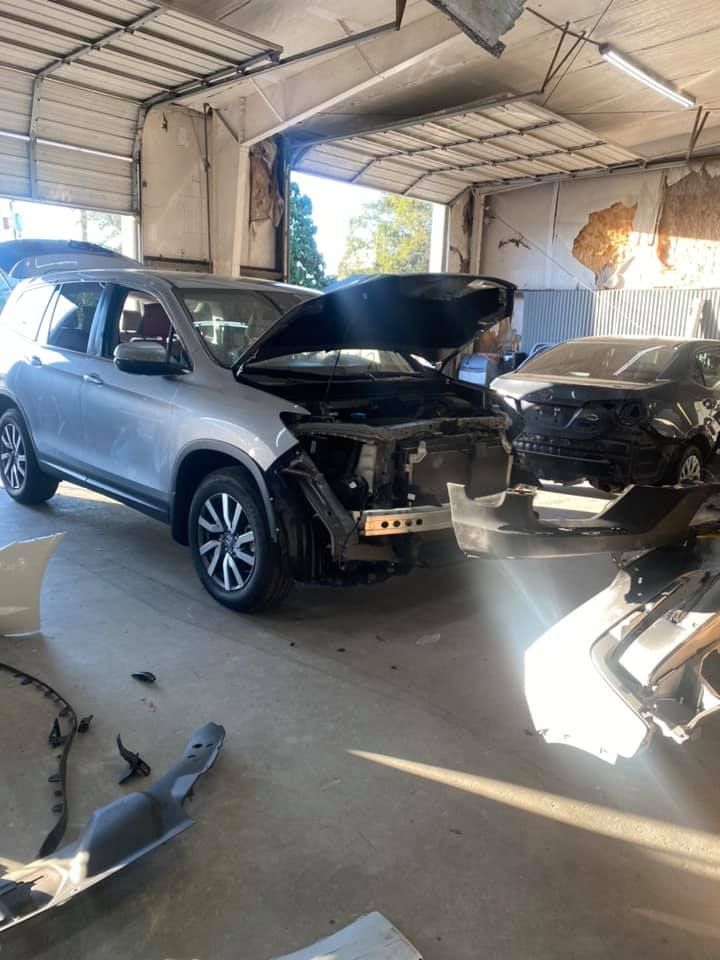a car with its hood up is sitting in a garage next to another car .