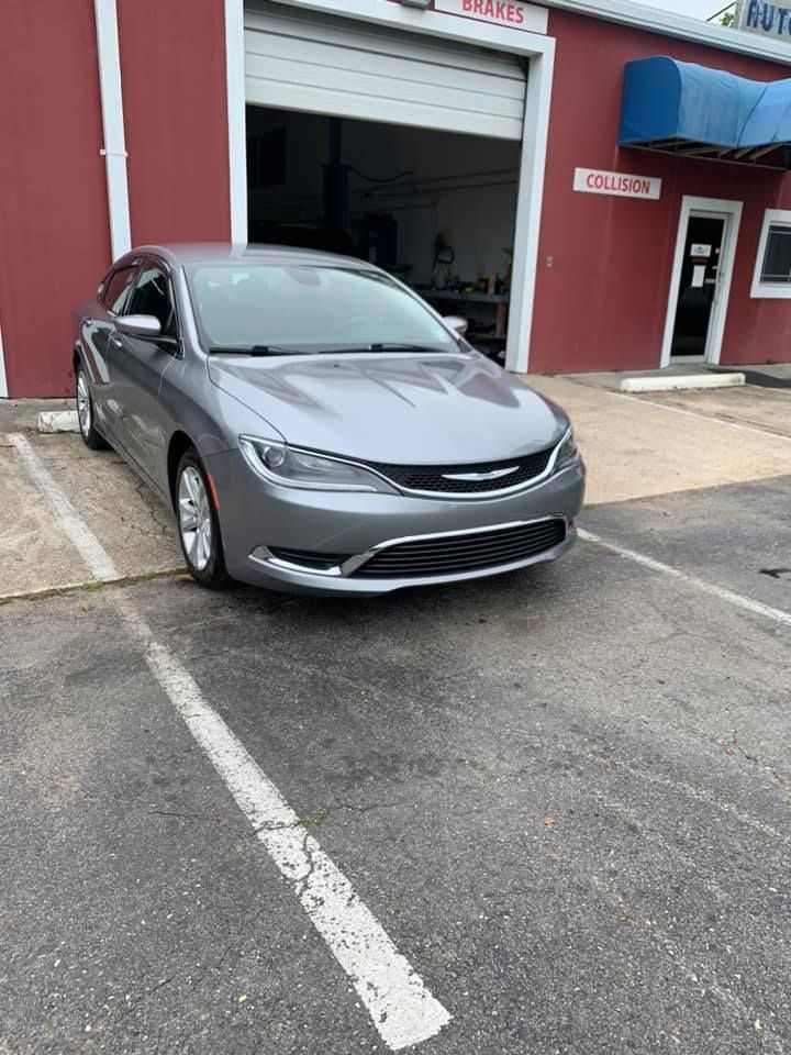 a gray chrysler pacifica is parked in a parking lot in front of a red building .