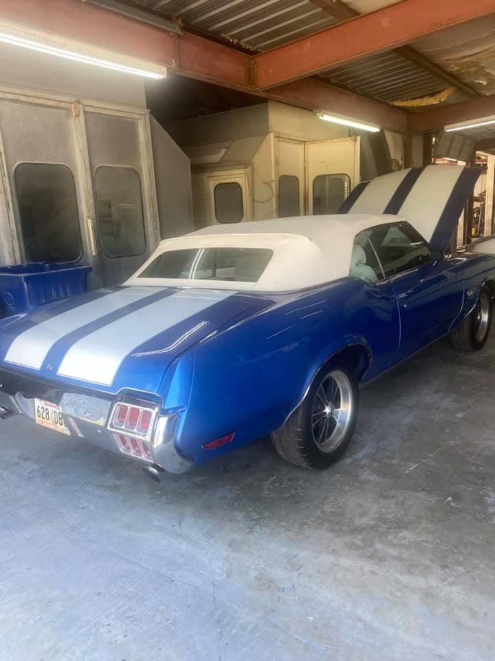 a blue and white car with the hood up is parked in a garage .