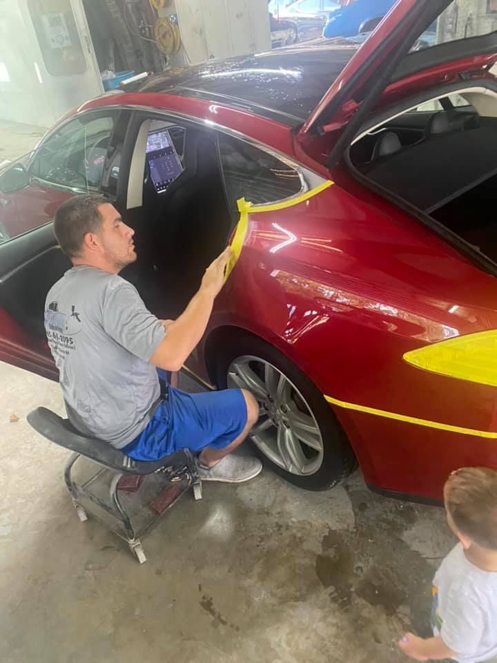 a man is sitting in a chair working on a red car .