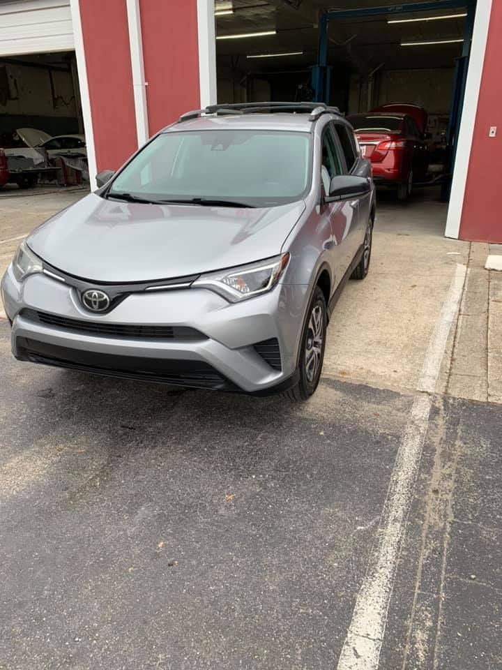a silver toyota rav4 is parked in a parking lot in front of a garage .
