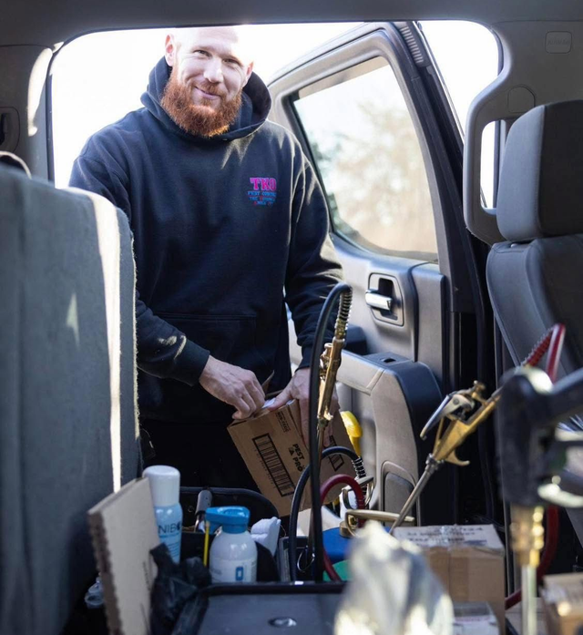 Person in a car trunk loading tools and supplies into the cargo area.