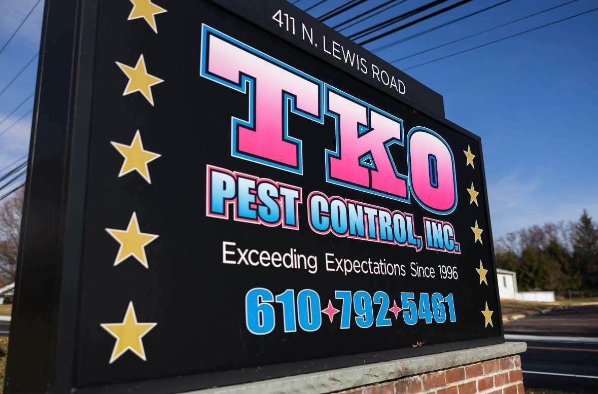 Tko Pest Control sign with stars, logo, and phone number on a black roadside sign