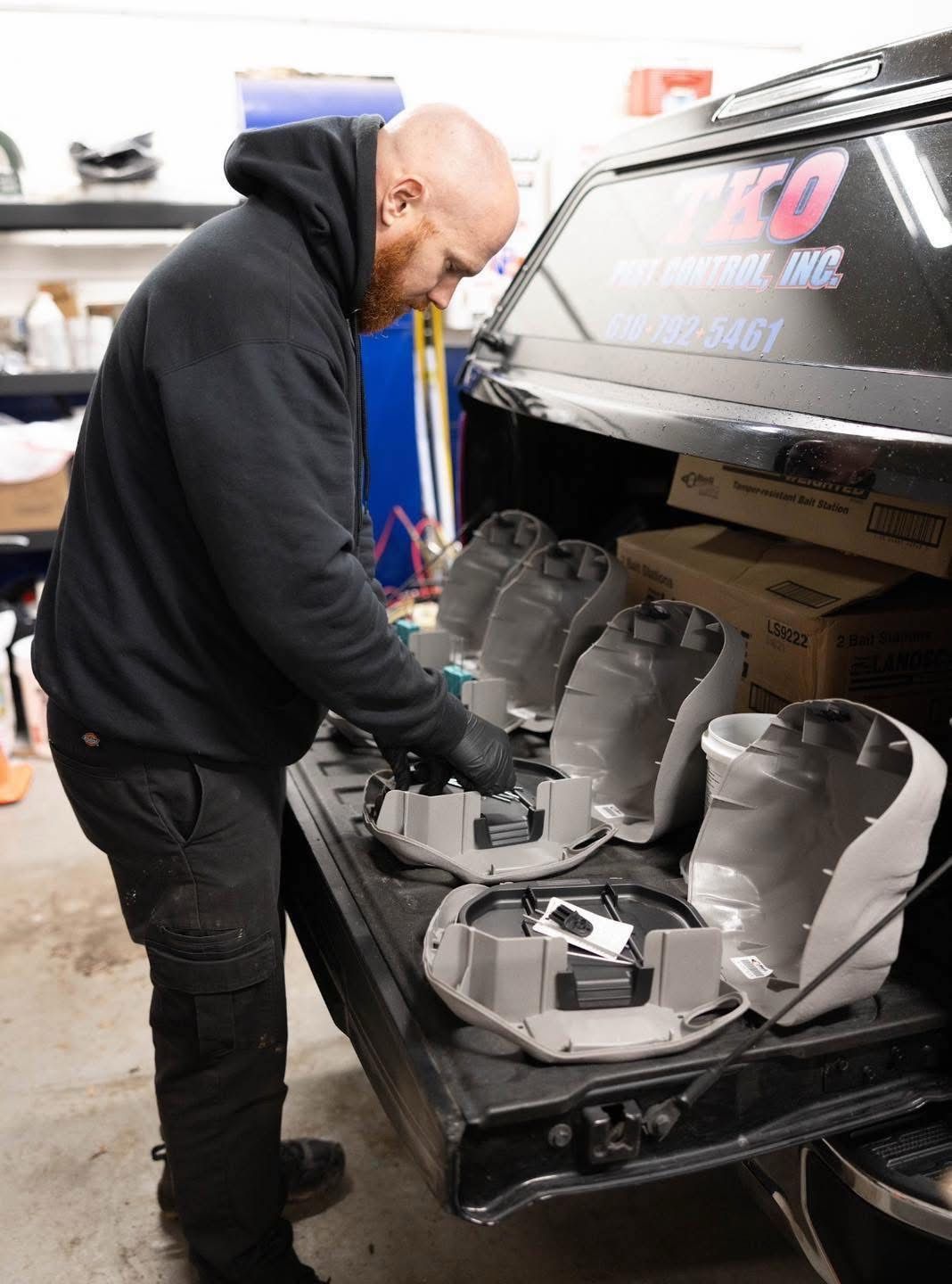 Mechanic inspecting the interior of a black car with exposed seats in a garage