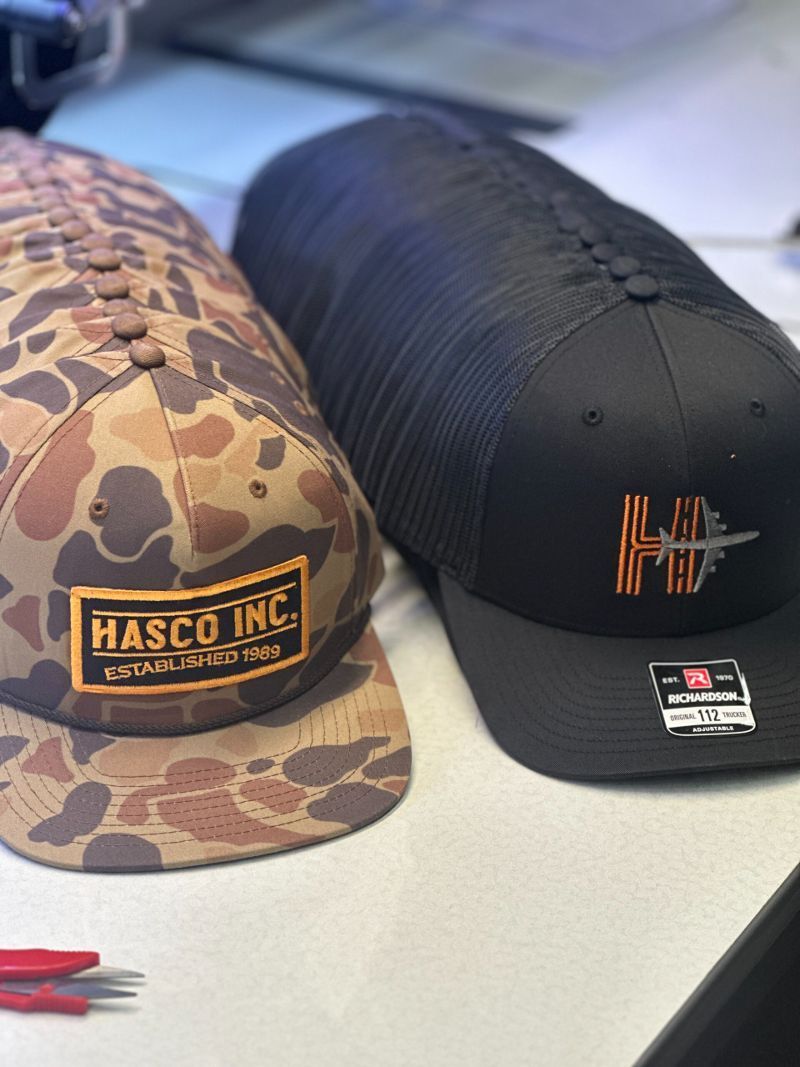 A stack of hats with one that says masco inc on it