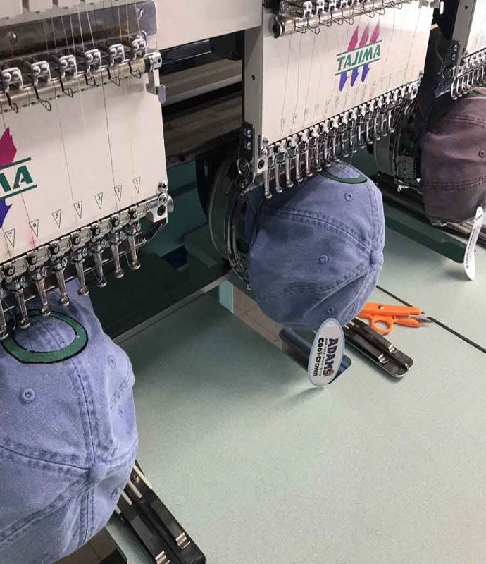 Two purple hats are being embroidered on a machine