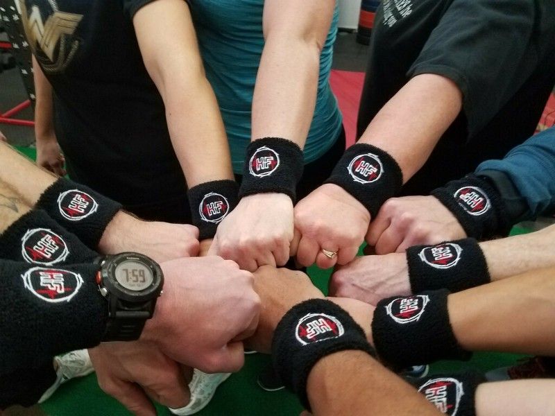 A group of people are putting their hands together and wearing wristbands with the letters bb on them