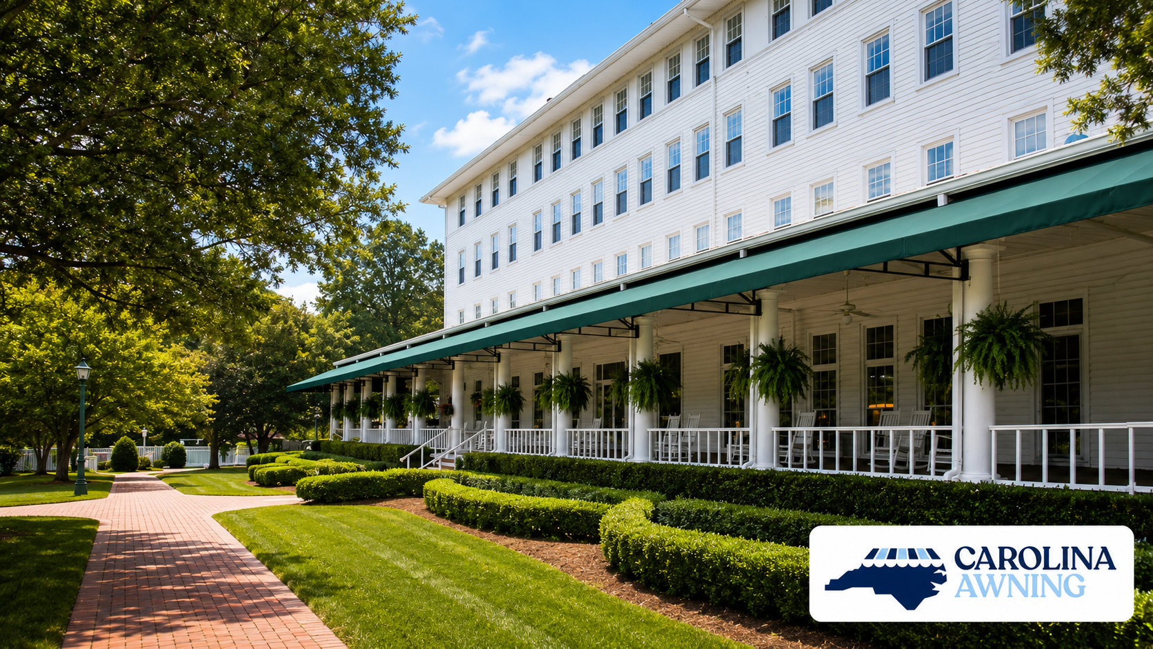 White multi-story building with green awnings, landscaped lawn, and Carolina Awning logo in the corner