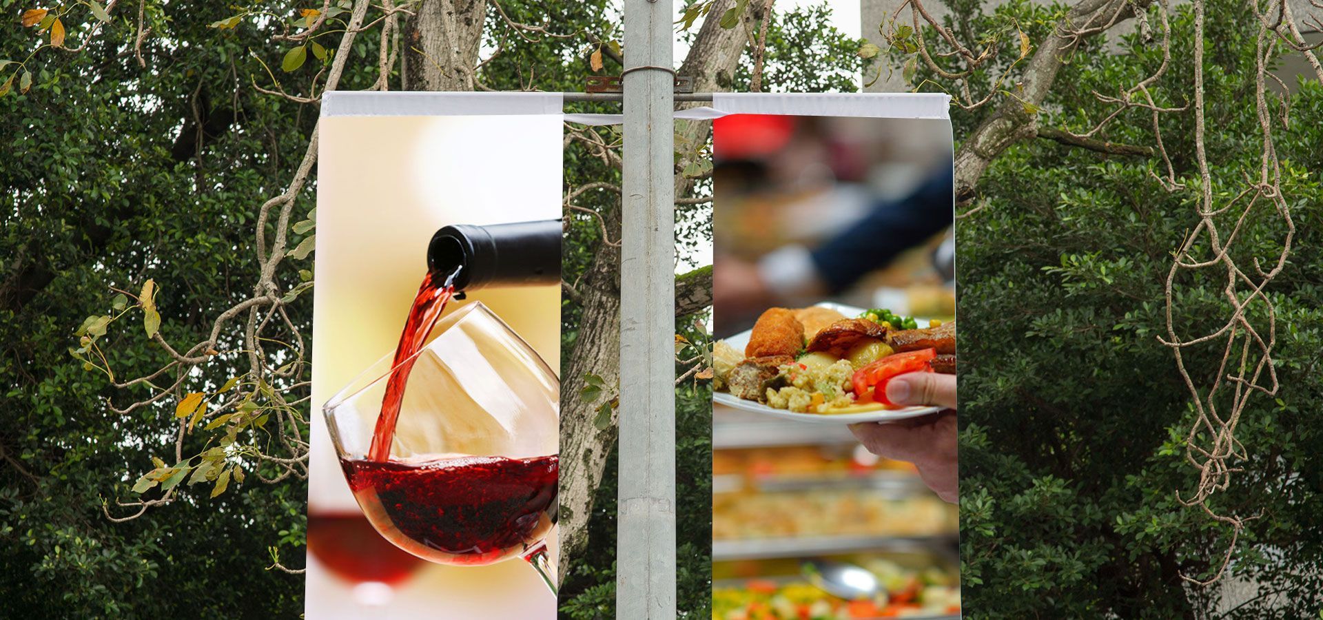 Wine glass and platter of food on hanging panels against a leafy outdoor background