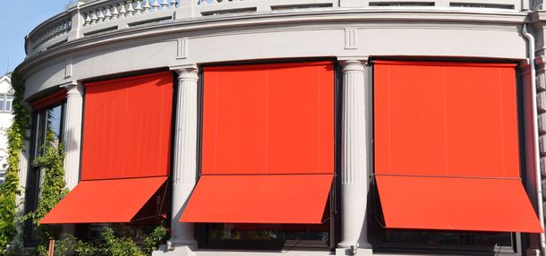 Storefront with three bright red awnings on a white building facade