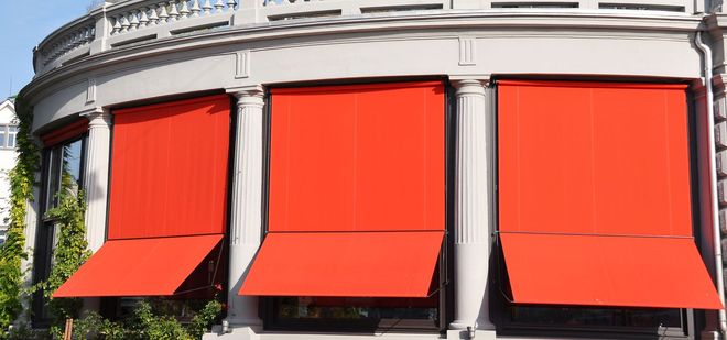 Storefront with three bright red awnings on a white building facade