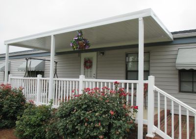 White porch with railing and hanging flowers on a house exterior