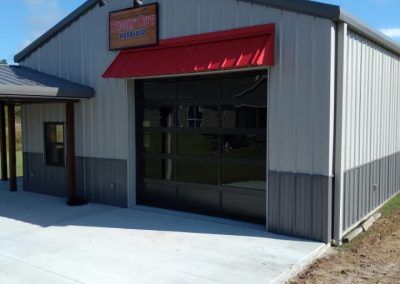 Small metal storefront with a red awning and large black-framed glass entrance