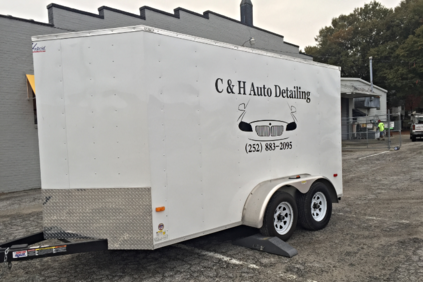 White enclosed trailer for C & H Auto Detailing with black logo and twin axles parked outdoors