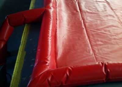 Red inflatable bounce house corner with blue entrance mat indoors